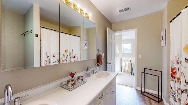 bathroom featuring wood finished floors, visible vents, a sink, and double vanity