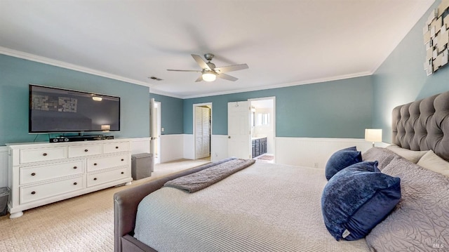 bedroom featuring a ceiling fan, visible vents, a wainscoted wall, and light carpet