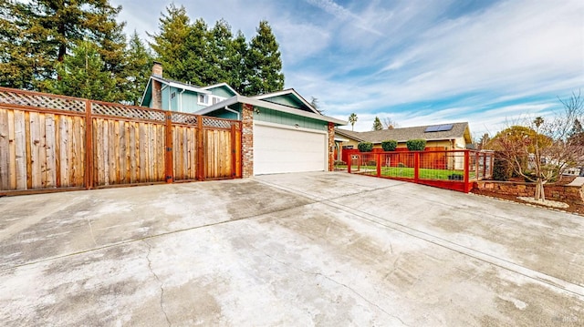 view of side of property featuring an attached garage, fence private yard, and concrete driveway