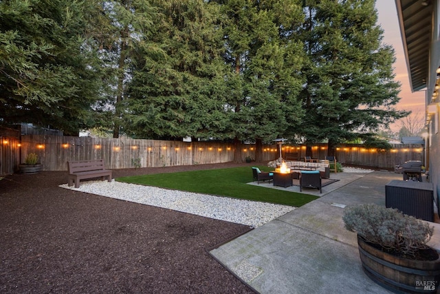 yard at dusk with an outdoor living space with a fire pit, a patio, and a fenced backyard