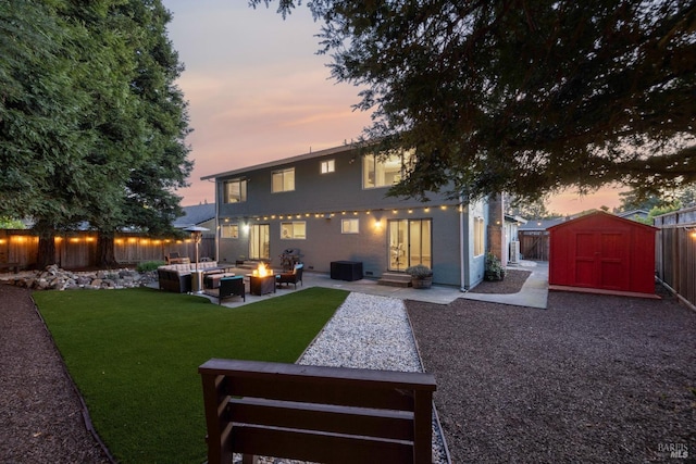 back of property at dusk featuring a patio area, an outdoor structure, a fenced backyard, and a storage shed