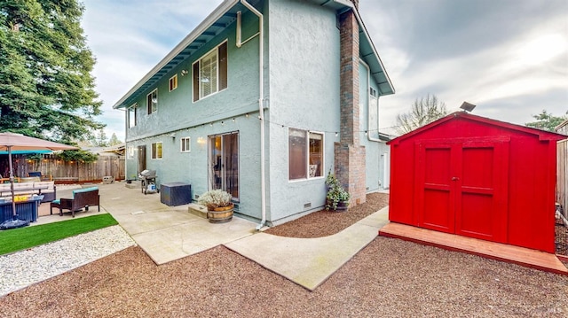 rear view of house with a patio, outdoor lounge area, an outdoor structure, stucco siding, and a storage unit