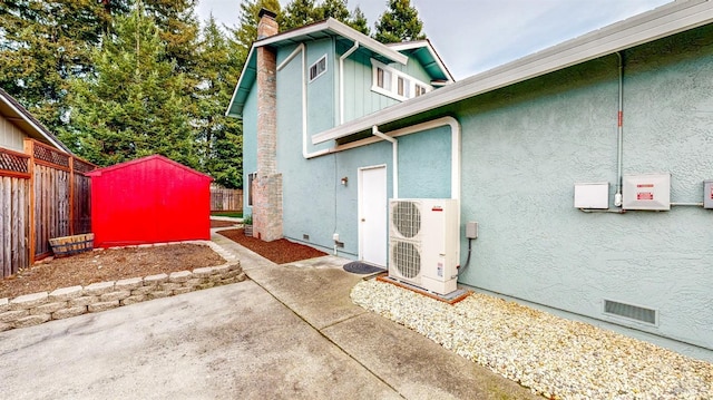 view of side of home featuring fence, crawl space, stucco siding, ac unit, and a chimney