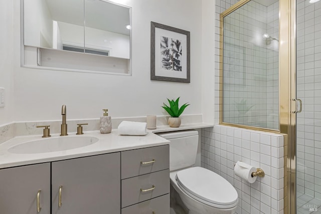 full bathroom with a stall shower, vanity, toilet, and tile walls