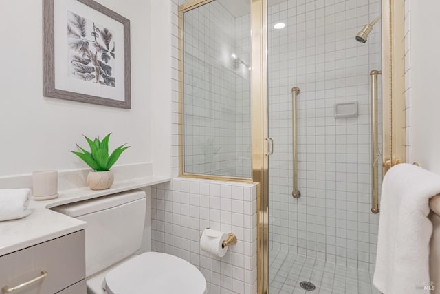 bathroom featuring toilet, a shower stall, and vanity