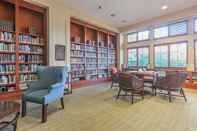 living area with built in features, recessed lighting, light carpet, and wall of books