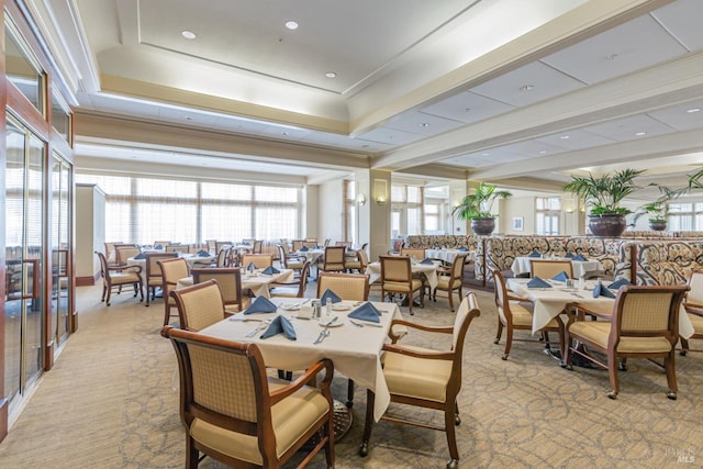 dining space featuring a raised ceiling, light colored carpet, and crown molding