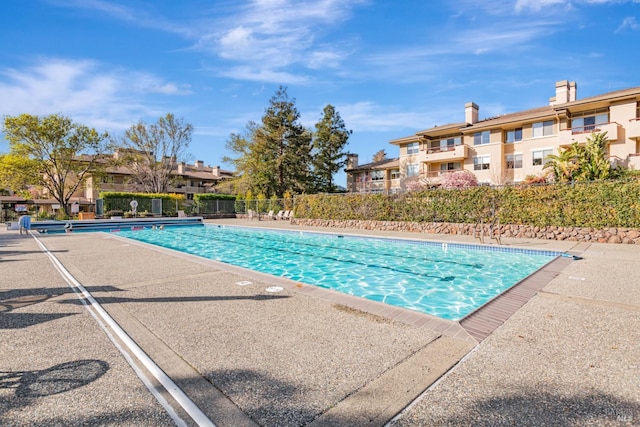 community pool featuring a residential view, fence, and a patio