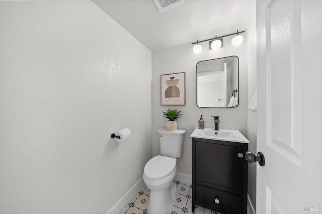 half bathroom featuring vanity, visible vents, baseboards, and toilet