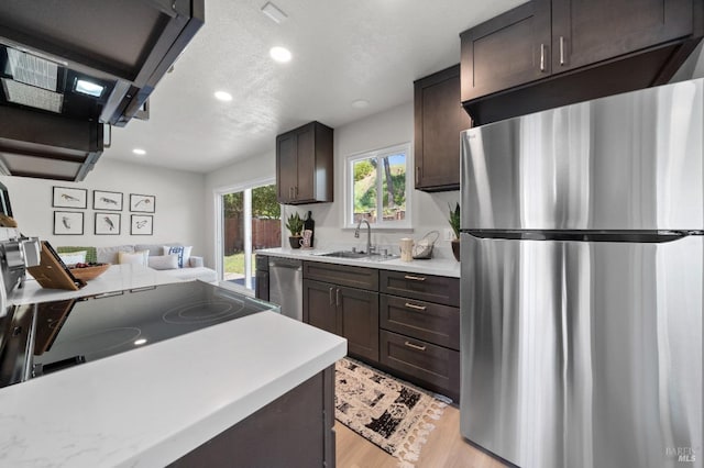 kitchen featuring recessed lighting, light countertops, dark brown cabinets, appliances with stainless steel finishes, and a sink