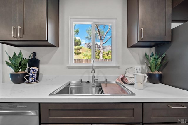 kitchen featuring light countertops, dark brown cabinets, stainless steel dishwasher, and a sink