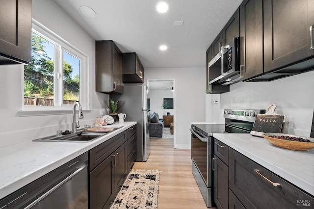 483 Rinconada Ct, Benicia, CA 94510 - kitchen with appliances with stainless steel finishes, a sink, light wood-type flooring, dark brown cabinets, and light stone countertops