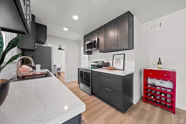 kitchen featuring light wood-type flooring, visible vents, appliances with stainless steel finishes, a sink, and baseboards