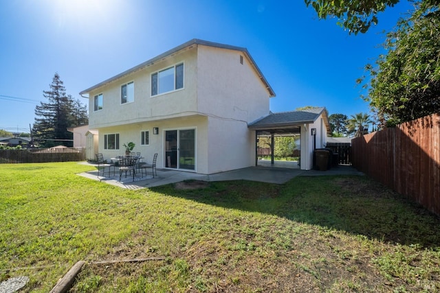 rear view of house with a yard, a patio area, a fenced backyard, and stucco siding
