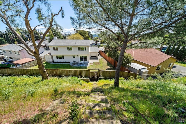 back of house with a fenced backyard, a chimney, and a lawn