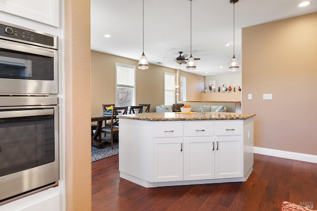 kitchen with dark wood-style floors, white cabinets, stainless steel double oven, and decorative light fixtures