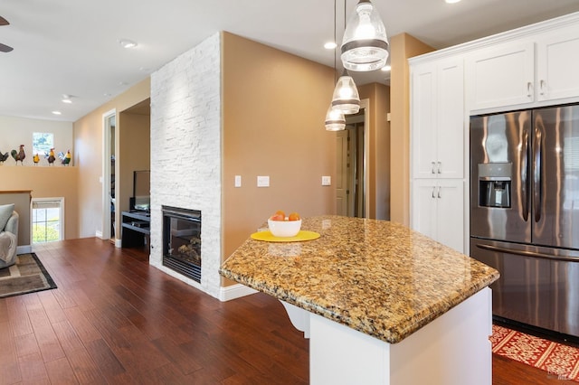 kitchen featuring stone counters, dark wood finished floors, a fireplace, stainless steel refrigerator with ice dispenser, and white cabinets