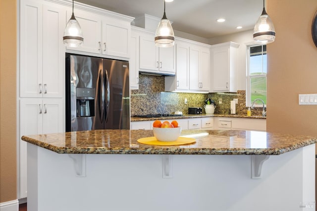 kitchen featuring stainless steel fridge, white cabinets, and pendant lighting