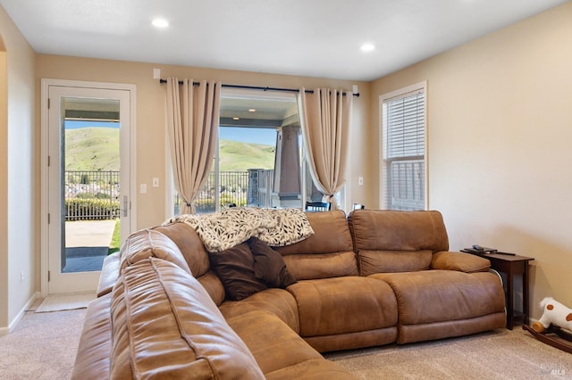 living room featuring a healthy amount of sunlight, light carpet, and a mountain view