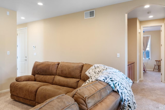 living area featuring arched walkways, baseboards, visible vents, and light colored carpet