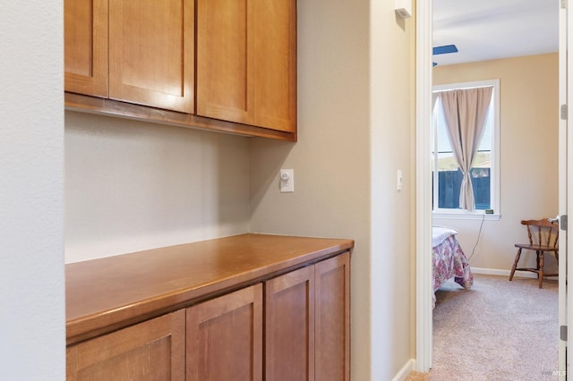 hallway with baseboards and light colored carpet