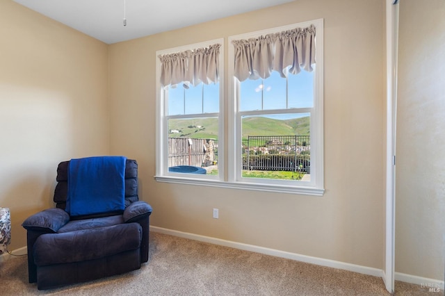 sitting room featuring carpet floors, a wealth of natural light, a mountain view, and baseboards