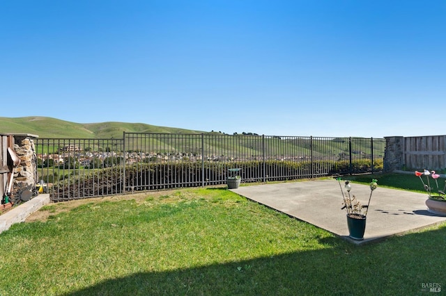 view of yard featuring a rural view, fence, a mountain view, and a patio