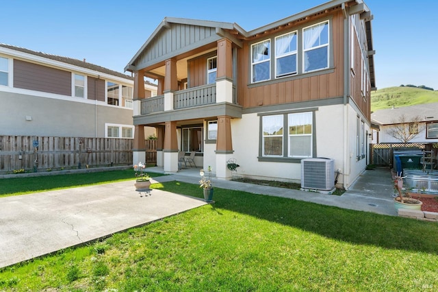 back of property featuring a patio, a balcony, fence, a yard, and central air condition unit