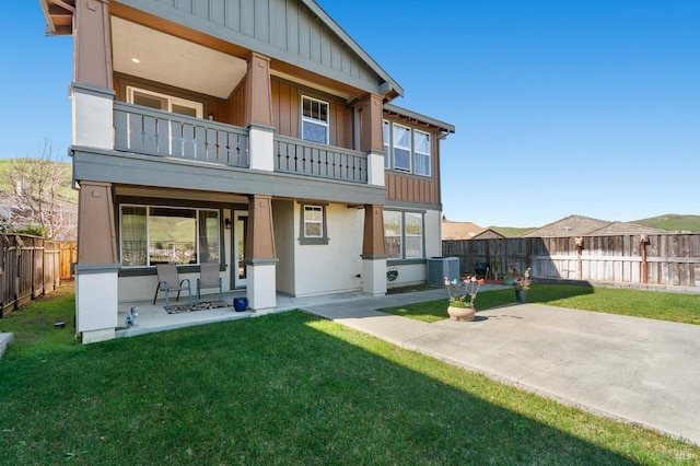 back of property with board and batten siding, a patio area, and a balcony