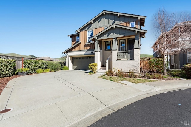 craftsman-style house with board and batten siding, driveway, an attached garage, and fence