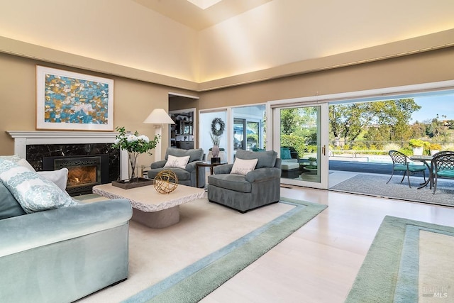 living area featuring a towering ceiling, wood finished floors, and a high end fireplace