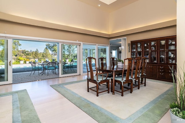 dining area with light wood-type flooring, a high ceiling, and plenty of natural light