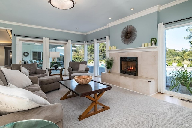 living area featuring a tiled fireplace, visible vents, and crown molding