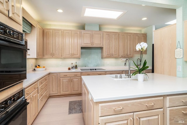 kitchen featuring a sink, black appliances, light brown cabinetry, and light countertops