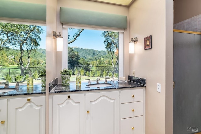 kitchen featuring white cabinets, a sink, dark stone countertops, and a mountain view