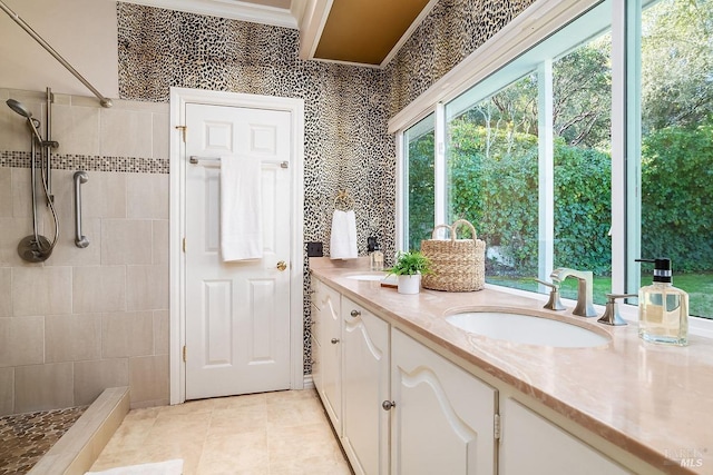 bathroom featuring double vanity, tile patterned flooring, a tile shower, crown molding, and a sink