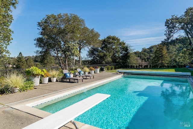 view of pool featuring fence, a diving board, a fenced in pool, and a patio