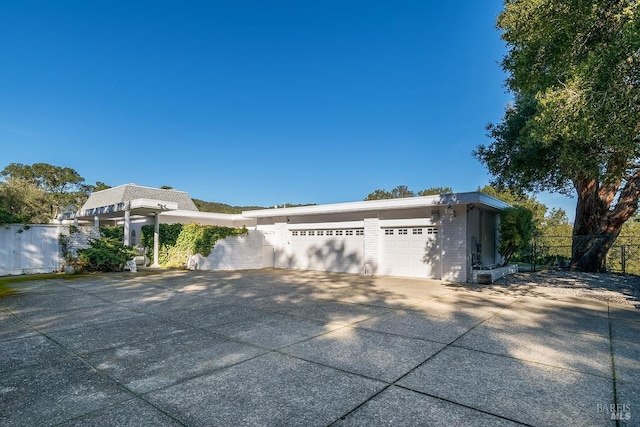 view of front facade featuring a garage, fence, and concrete driveway