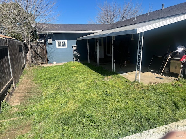 rear view of property featuring a patio, fence, a lawn, roof with shingles, and stucco siding