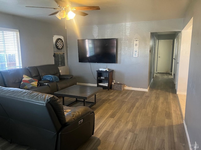 living area featuring a ceiling fan, baseboards, and wood finished floors