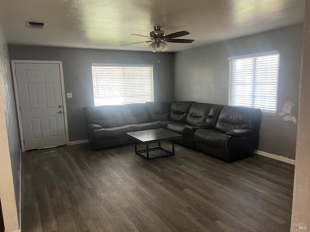 living room with dark wood-style floors, visible vents, and baseboards