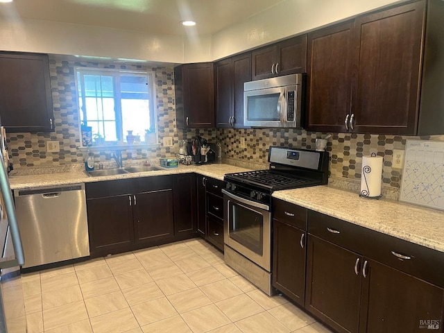 kitchen featuring decorative backsplash, stainless steel appliances, a sink, and light countertops