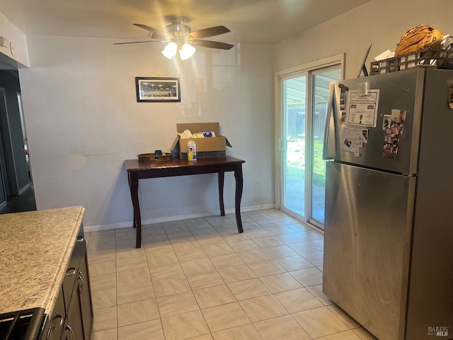 kitchen with light tile patterned floors, baseboards, ceiling fan, freestanding refrigerator, and light countertops