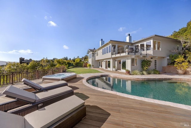 view of swimming pool with a fenced in pool, hot tub deck surround, and a deck