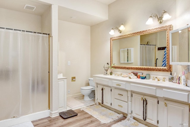 bathroom with visible vents, a sink, a shower stall, and wood finished floors