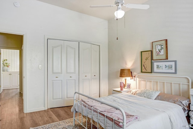 bedroom with light wood-style floors, ceiling fan, baseboards, and a closet