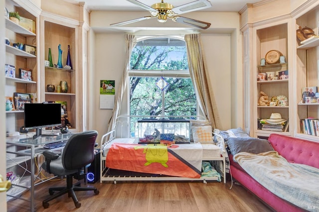 office area with built in shelves, a ceiling fan, and wood finished floors