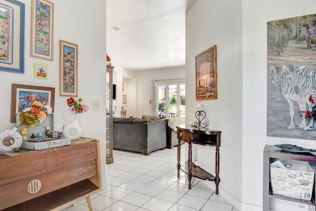 hall featuring baseboards, a textured ceiling, and light tile patterned flooring