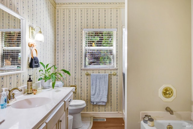 full bathroom with a washtub, visible vents, toilet, vanity, and wallpapered walls