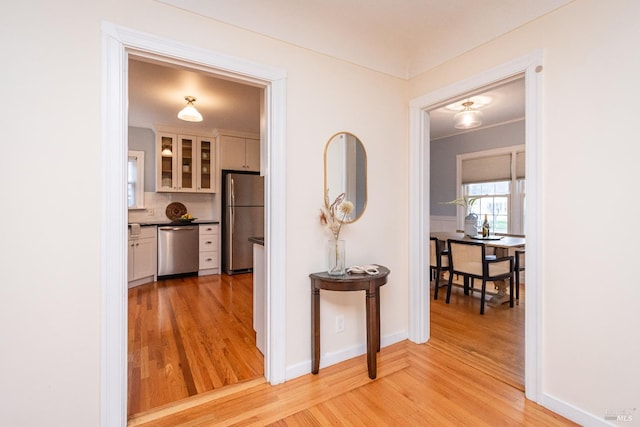 hall with light wood-style flooring and baseboards